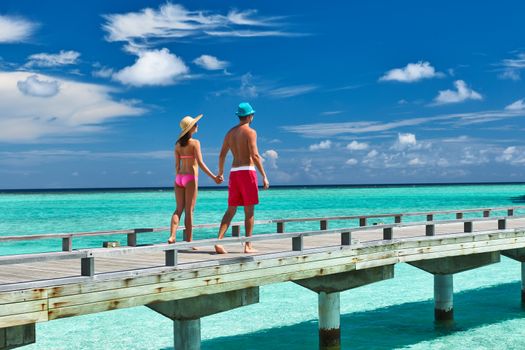 Couple on a tropical beach jetty at Maldives