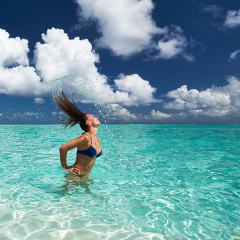 Woman splashing water with her hair in the ocean