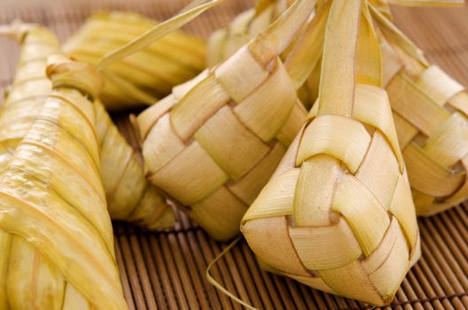 Ketupat or packed rice dumpling. Delicious traditional Malay ramadan food. Popular Malaysian food on bamboo mat.