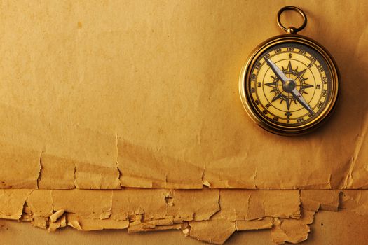 Antique brass compass over old paper background