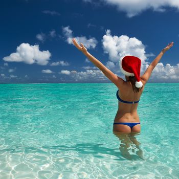 Woman in santa's hat in bikini at tropical beach