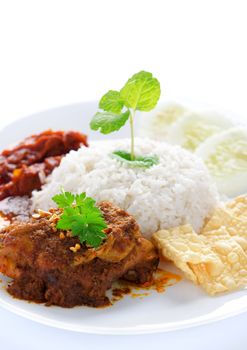 Nasi lemak kukus traditional malaysian spicy rice dish. Served with belacan, ikan bilis, acar, peanuts and cucumber. White background.