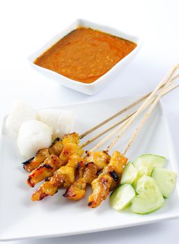 Chicken satay, skewered and grilled meat, served with peanut sauce, cucumber and ketupat. Traditional Malay food. Delicious hot and spicy Malaysian dish, Asian cuisine.