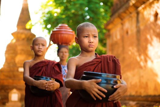 Young Buddhist monks walking morning alms in Old Bagan, Myanmar