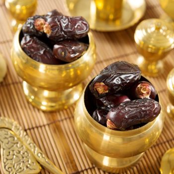 Dried date palm fruits or kurma, ramadan food which eaten in fasting month. Pile of fresh dried date fruits in golden metal bowl.