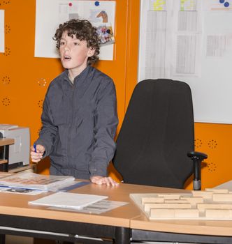boy standing behind the desk in classroom