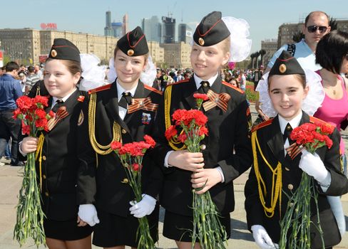 Moscow, Russia - May 9, 2013: Four young girls in uniform decorated with bearing bunch of flowers during festivities devoted to 68th anniversary of Victory Day.