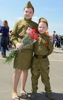Moscow, Russia - May 9, 2013: Brother and sister in uniform decorated with bearing bunch of flowers during festivities devoted to 68th anniversary of Victory Day.