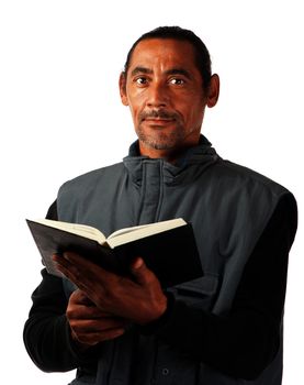 An adult male holds a book in his hands.
