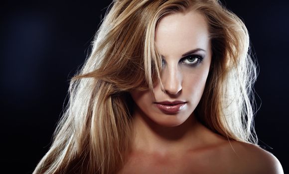 Sexy Caucasian lady with perfect makeup and long hairs in the studio on a dark background