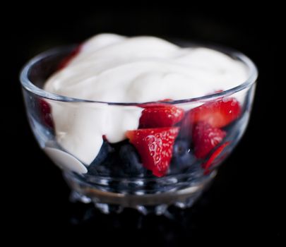 strawberry and blueberry yoghurt in a bow isolated on black background