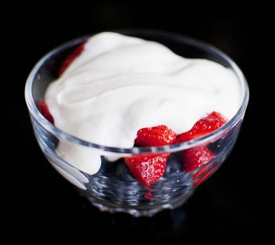 strawberry and blueberry yoghurt in a bow isolated on black background