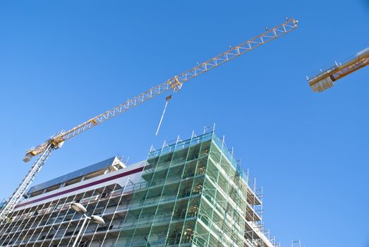 High-rise building construction site with cranes against blue sky