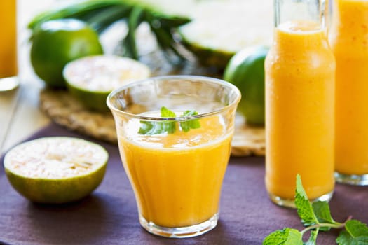 Pineapple with Orange and Mango smoothie in a glass and bottles