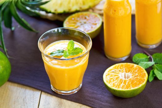 Pineapple with Orange and Mango smoothie in a glass and bottles