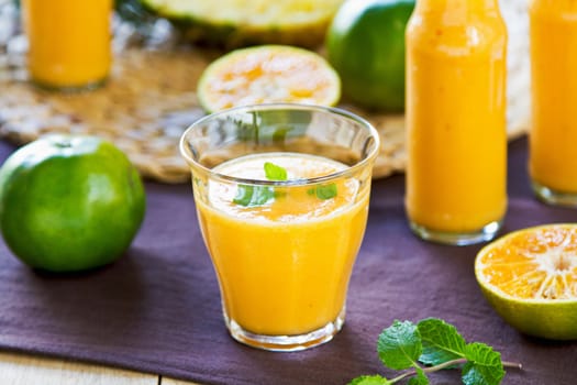 Pineapple with Orange and Mango smoothie in a glass and bottles