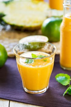 Pineapple with Orange and Mango smoothie in a glass and bottles