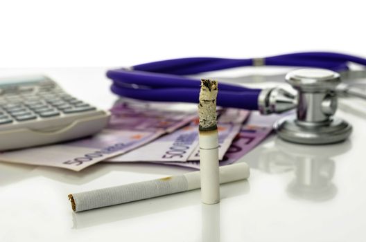 Cigarettes with Euro money, stethoscope and calculator in background. Representing big expenses and great health risk smoking causes.