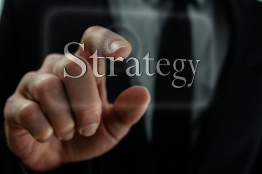 Closeup of businessman hand pressing Strategy icon on a virtual screen.