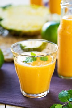 Pineapple with Orange and Mango smoothie in a glass and bottles