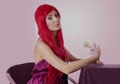 Red-haired sad woman with cocktail sitting at table
