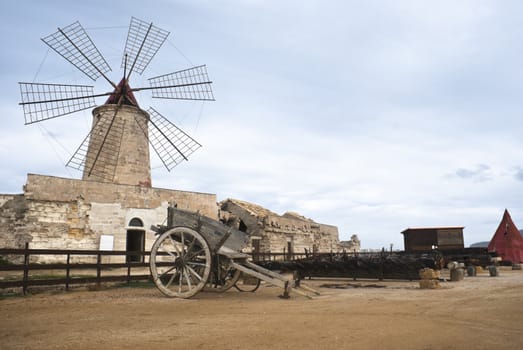 old windmill in sicily with old sicilian cart, trapani, italy