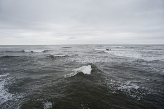 The stormy waves of the North Sea in a grey overcast day with a view of the horizon