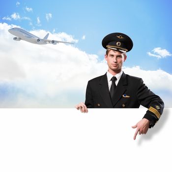 pilot in the form of holding an empty billboard on the background of sky and flying plane, place for text