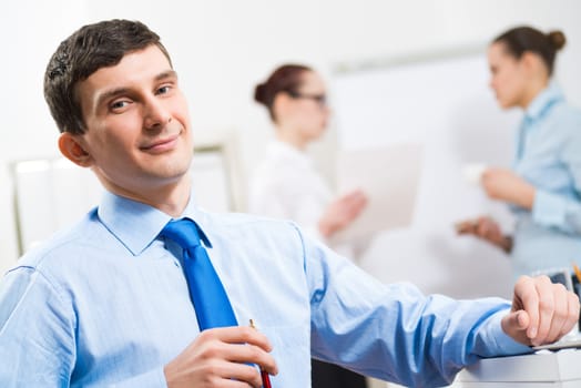 Portrait of a businessman in a blue shirt in the background of colleagues discussing