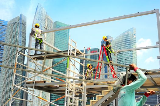 Singapore, Republic of Singapore - May 09, 2013: Workers at construction site in front of Singapore downtown. Construction industry is expected to pull in some S$30 billion this year