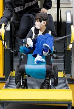 Disabled six year old boy riding on the school bus wheelchair lift, going to school