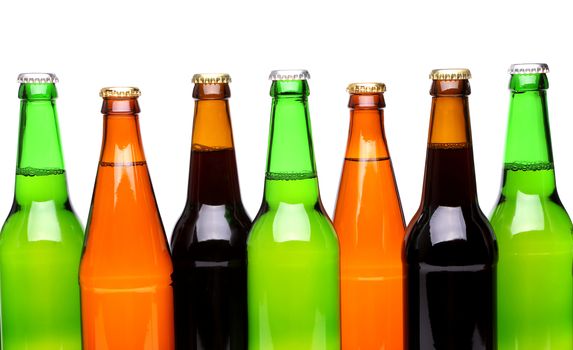 A row of top beer bottles on a white background with a reflection.