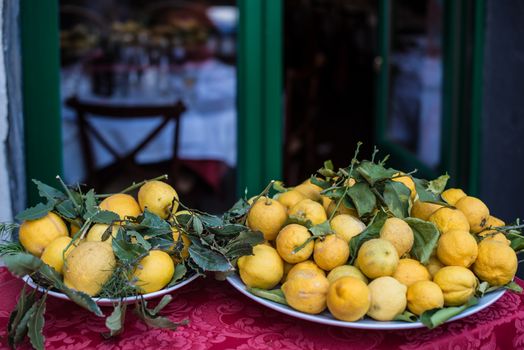 Plates with fresh lemons on red tablecoth in front of a cozy restaurant