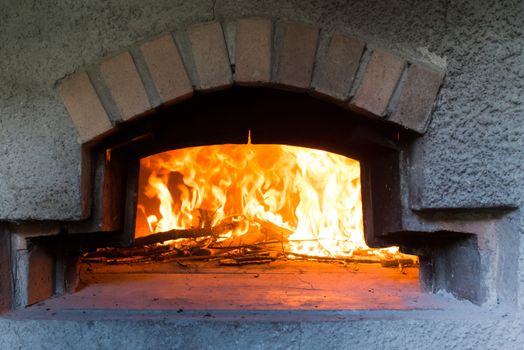 traditional Italian pizza wood oven with large fire in the background, ready for pizza to cook