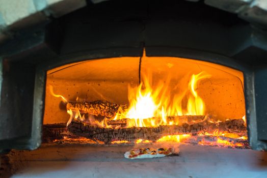 traditional Italian pizza wood oven with large fire in the background, ready for pizza to cook