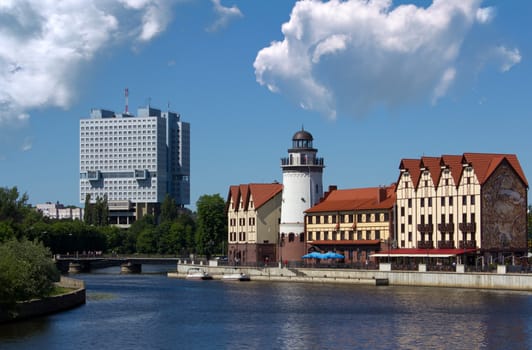 modern buildings and lighthouse on shore of the river on summer