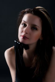 portrait of young beauty woman in black gloves posing on black background in studio