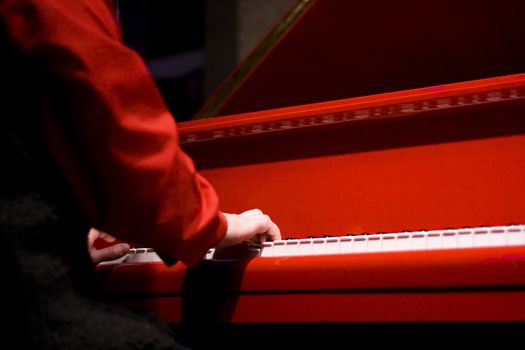 hands of the pianist at the red piano in concert hall