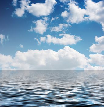 white clouds in the blue sky reflected in the water on summer day