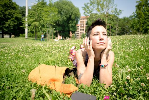 beautiful hipster short hair woman listening music in the park in the city