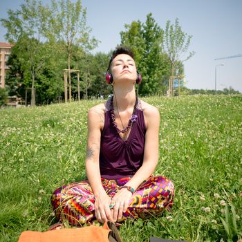 beautiful hipster short hair woman listening music in the park in the city