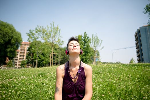 beautiful hipster short hair woman listening music in the park in the city