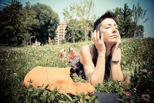 beautiful hipster short hair woman listening music in the park in the city