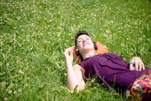 beautiful hipster short hair woman listening music in the park in the city