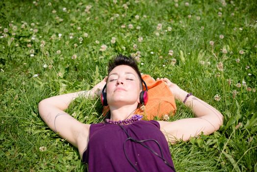beautiful hipster short hair woman listening music in the park in the city
