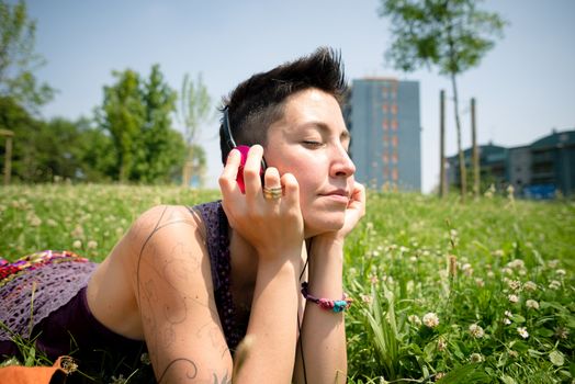 beautiful hipster short hair woman listening music in the park in the city