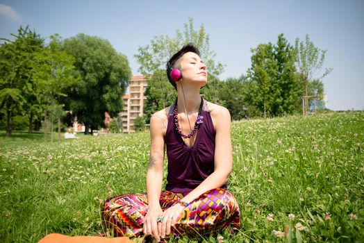 beautiful hipster short hair woman listening music in the park in the city