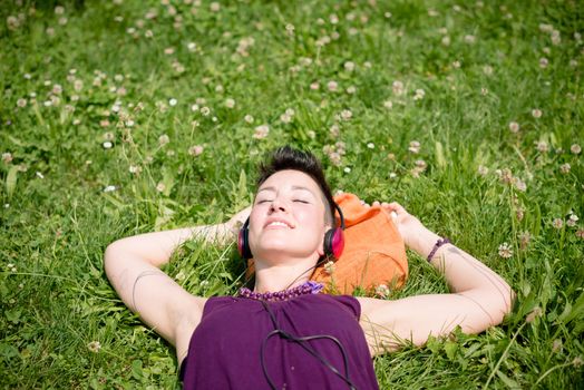 beautiful hipster short hair woman listening music in the park in the city