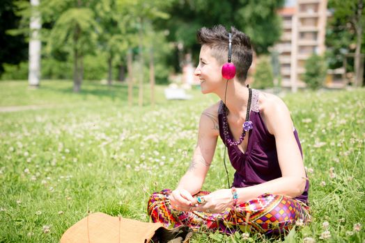 beautiful hipster short hair woman listening music in the park in the city