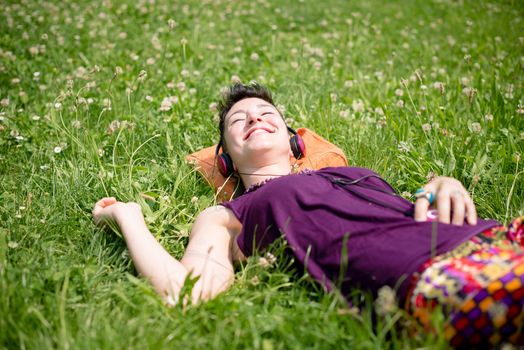 beautiful hipster short hair woman listening music in the park in the city